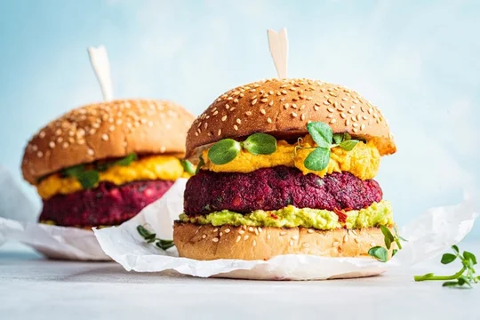 Two burgers with vegetables on them