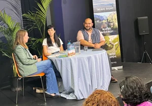 3 adults sitting at a table for a presentation.
