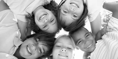 Children standing in a circle looking down into the camera and smiling.