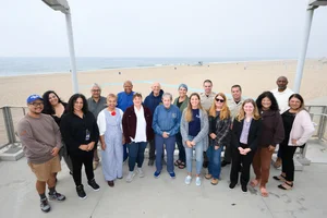 a group of people posing in front of the beach.