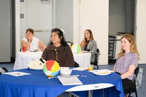4 women sitting at tables at an event