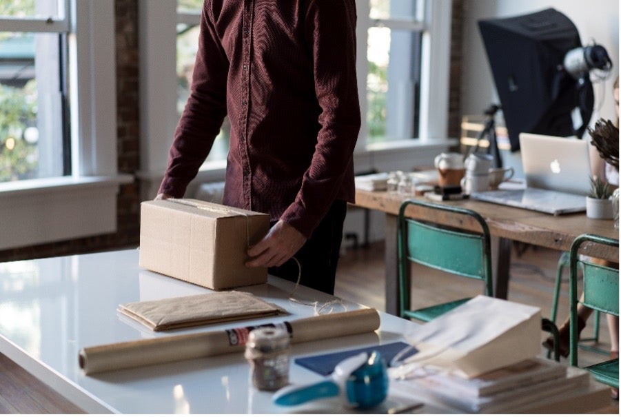 Man in a red shirt sets a box down on a table after his individual move to Seoul, South Korea with Atlas® International.