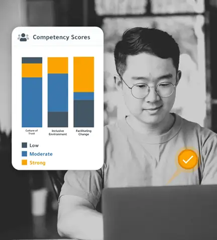 man leader looking happily at this laptop with his DDI leadership assessment scores, beside him a graphic that shows his competency scores in leadership skills surrounding creating a culture of trust, an inclusive environment, and facilitating change