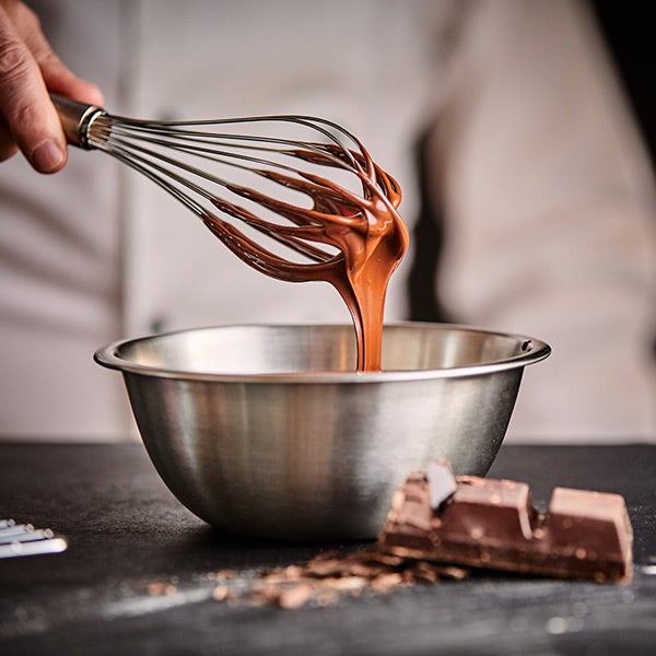 Chef mixing chocolate sauce in a mixing bowl.