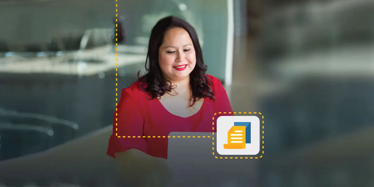 smiling woman looks down at computer to work on an executive leadership development program