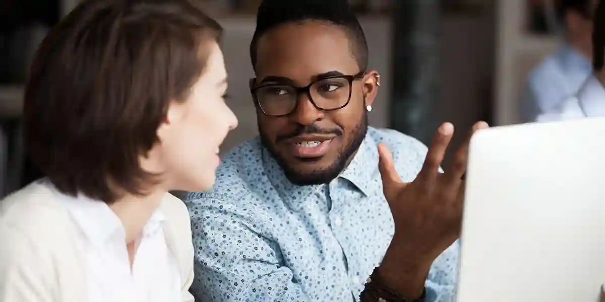 A coach helping an employee at a work station.