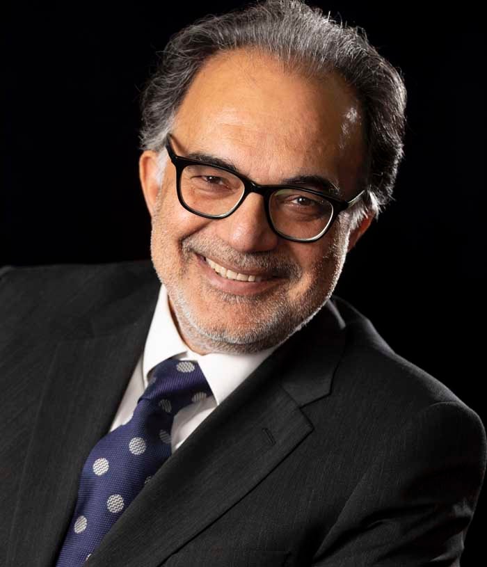 Ravi Mahajan, a man with graying dark hair, wears a dark suit, white shirt, and blue tie with silver polka dots.