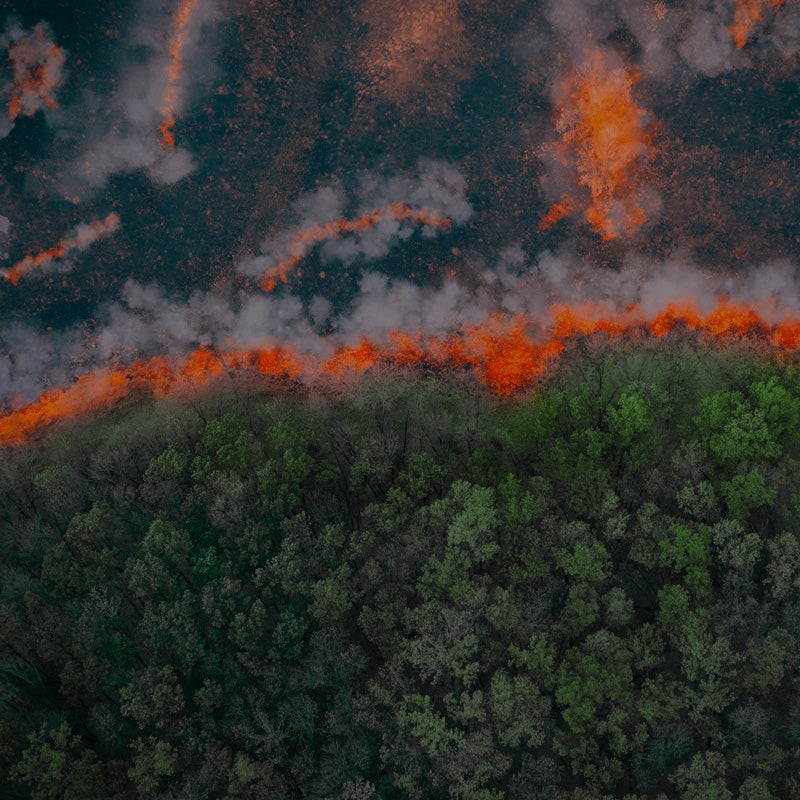 A wildfire pushes down through a forest, as seen from above