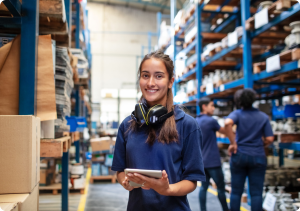 Young woman with headphones holding a tablet in a warehouse.
