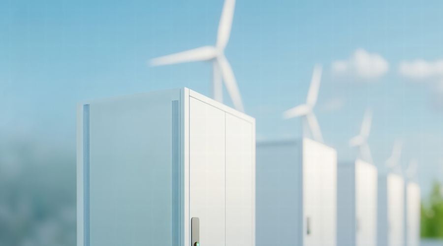 White data center cabinets aligned outdoors with wind turbines in the background, illustrating sustainable infrastructure and energy-efficient cabinet design.
