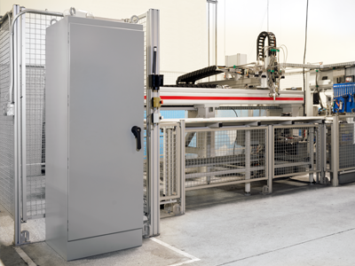 Gray server cabinet next to industrial machinery in a facility.