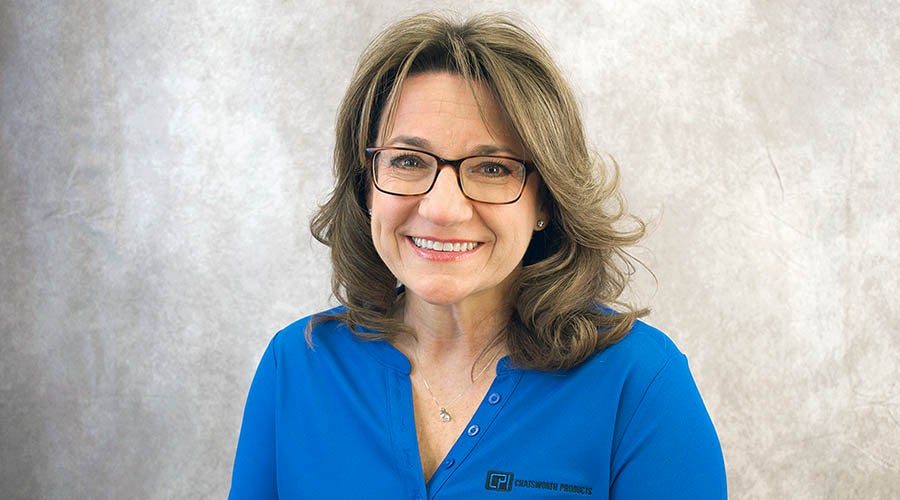 Kayla Hicks - Woman with wavy light brown hair and glasses, wearing a blue CPI-branded blouse, smiling in front of a light gray textured background.
