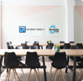 Meeting room with a long table, black chairs, and two wall-mounted signs.