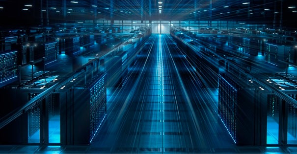 A data center with rows of server cabinets illuminated in blue light.