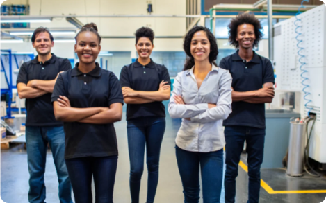 Group of five people standing in a workspace, arms crossed, smiling.