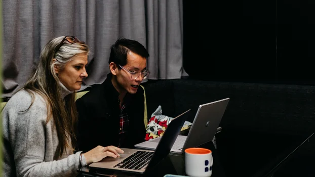 Man and woman having conversation over laptops