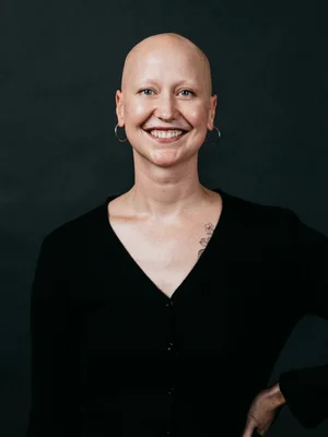 Picture of Luminary employee, Shayna smiling at the camera with a black background.