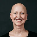 Picture of Luminary employee, Shayna smiling at the camera with a black background.