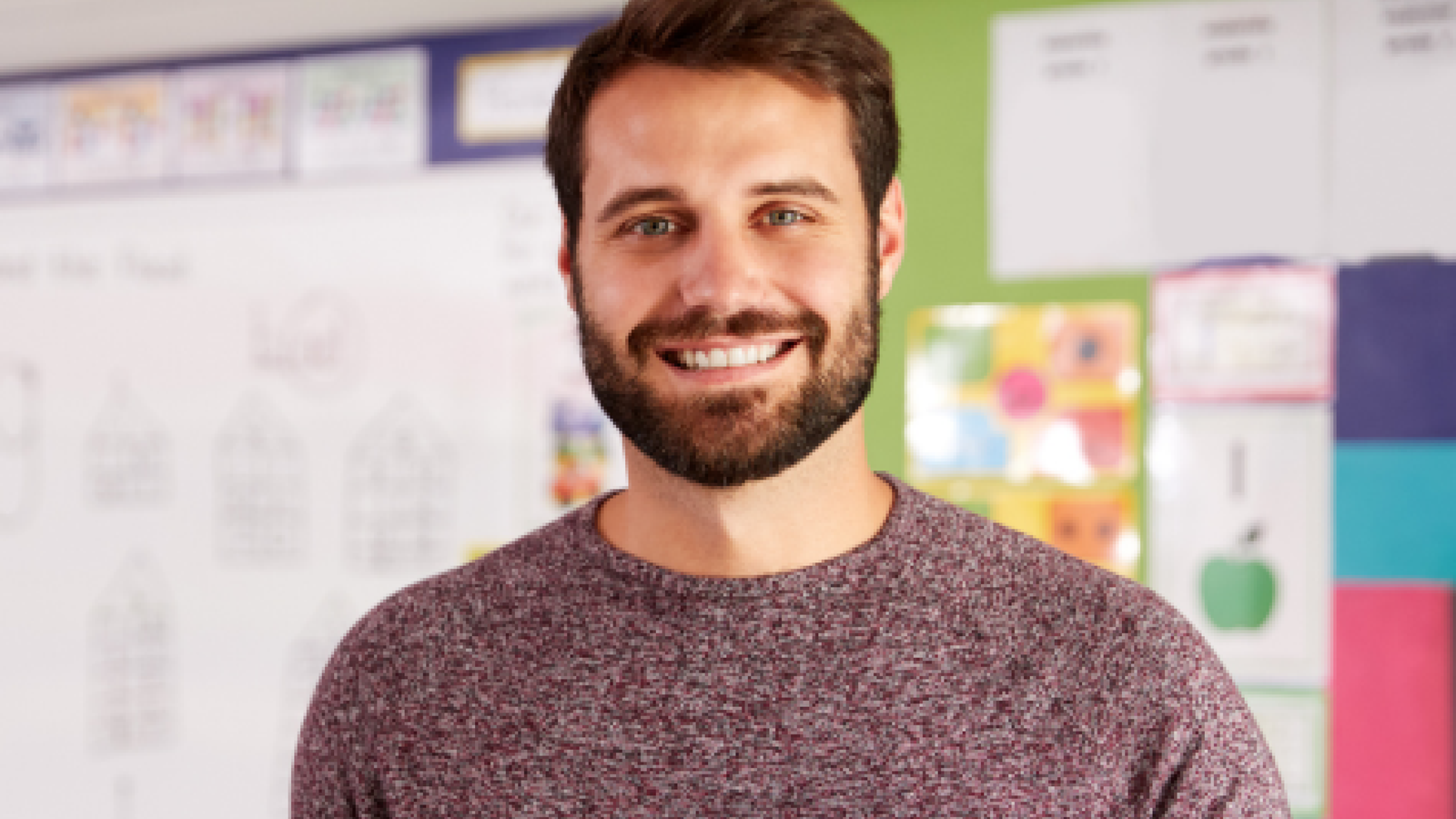 Picture of a student standing in a classroom holding a Pearson textbook