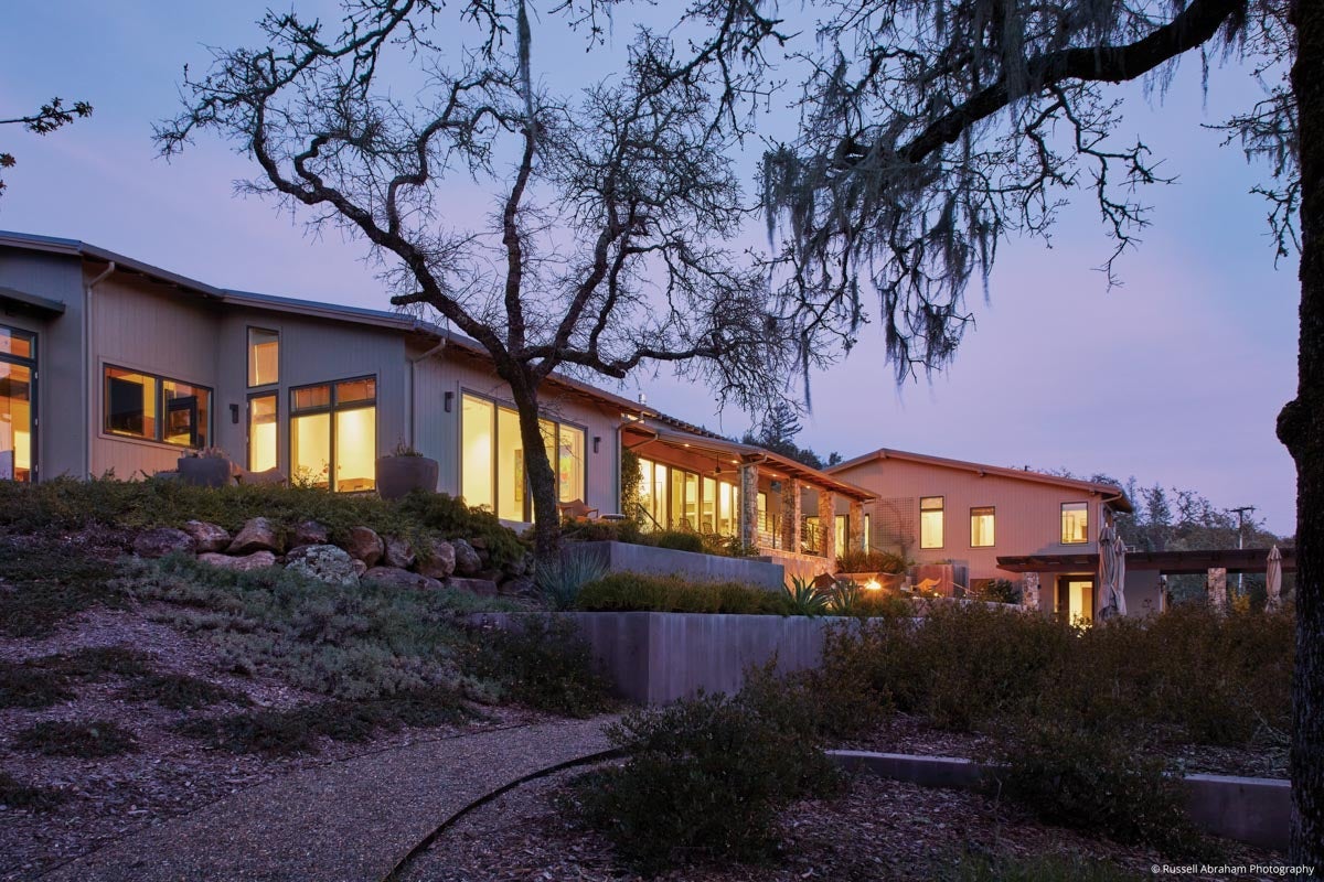 AM214 - rear view of large home at night with VistaLuxe WD casements, awnings, swing doors and sliding doors
