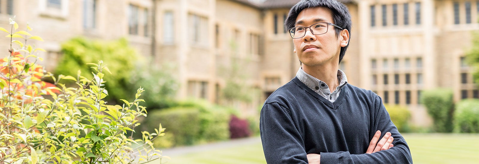 Student outside looking toward campus with their arms folded