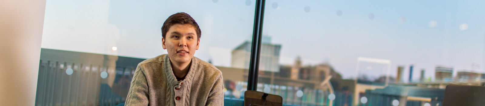 A student in a bright, glass room on Aberdeen's campus.