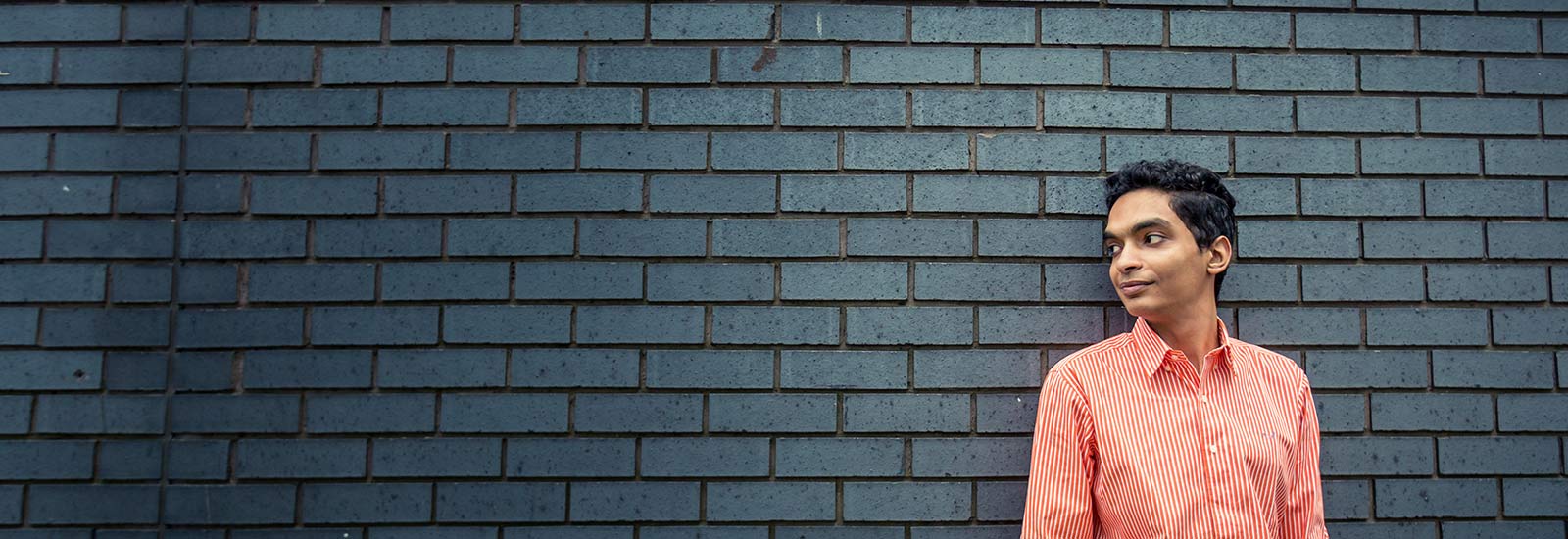 A student stood in front of a wall on LJMU's campus.
