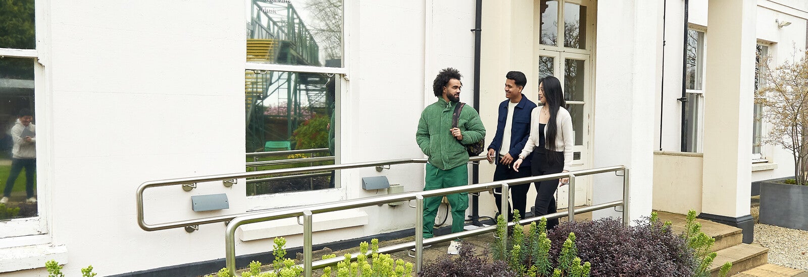 Three students walking out of a campus building