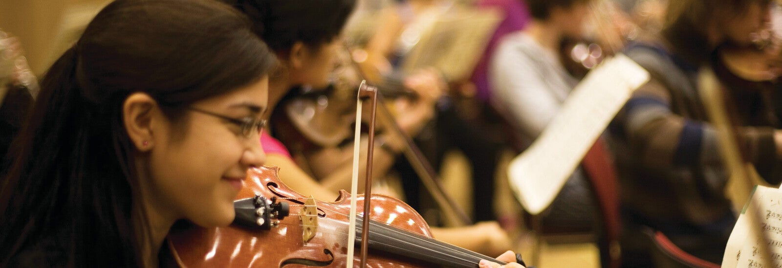 A student playing the violin in a band.