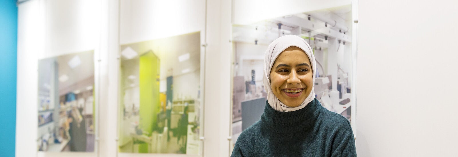 Student smiling and leaning against wall on campus
