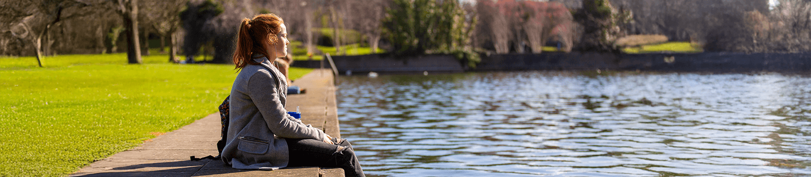 A student sitting by a lake