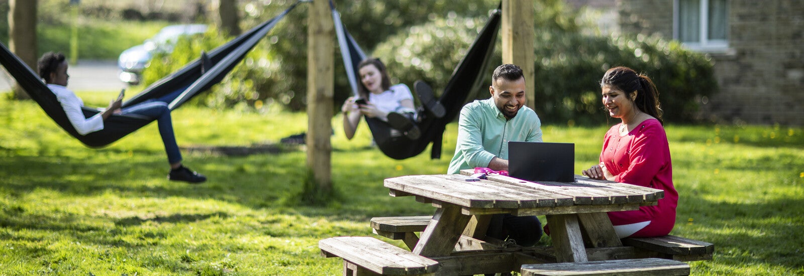 Students working on laptop together on a bench outside