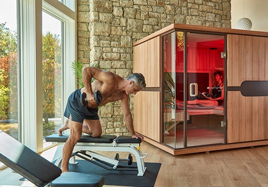 Man exercising. Woman reading in Sunlighten sauna.