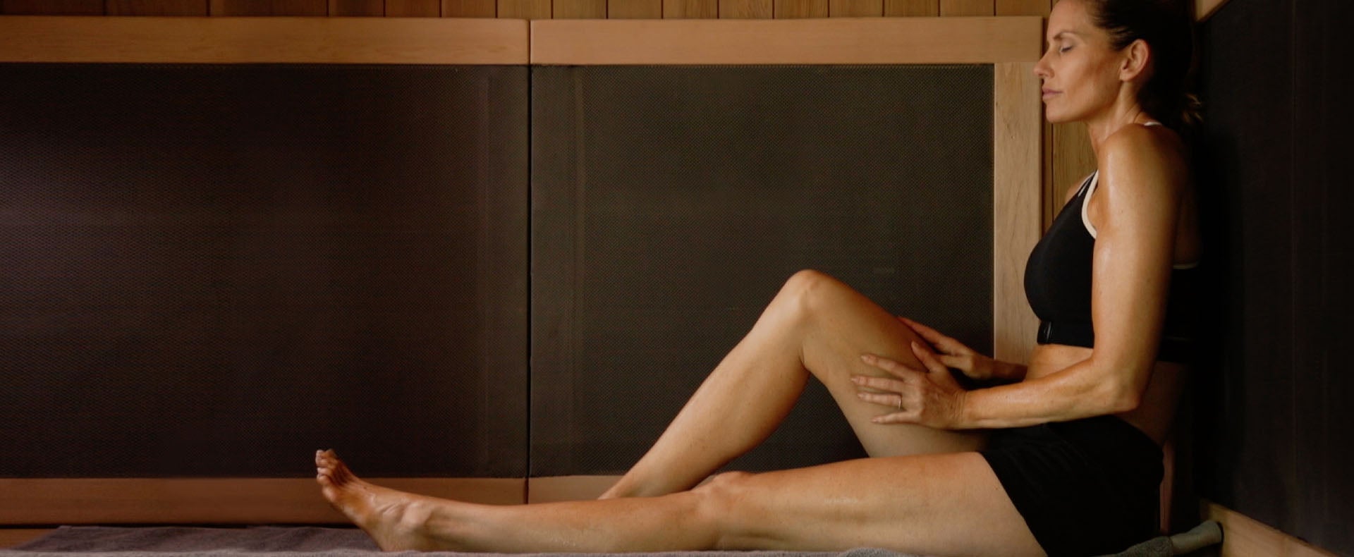 woman sits in infrared sauna relaxing