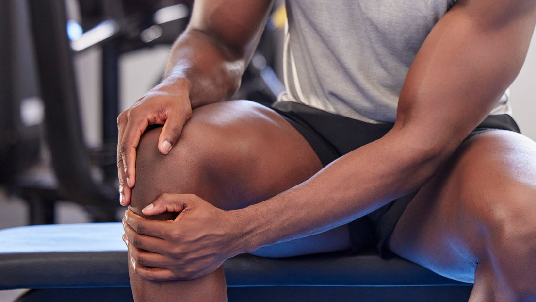 A man rubs his knee after exercising. 