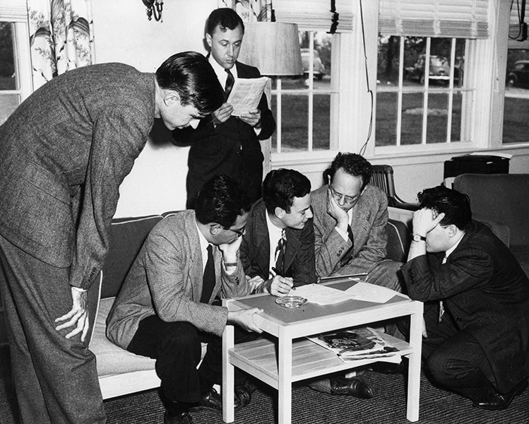Renormalization in progress at the Shelter Island Conference, 1947; Feynman, in the center on the couch, draws diagrams for Schwinger, at right on the floor, while another prodigy, John Wheeler, does his own thing at the back; Willis Lamb, whose discovery of the Lamb shift was a major topic of discussion at Shelter Island, stands at left;  photograph property of the Julian Schwinger Foundation (schwingerfoundation.org)