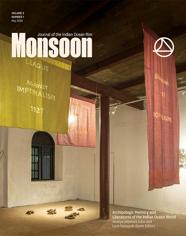 Cover of "Archipelagic Memory and Literatures of the Indian Ocean World," a special issue of Monsoon, volume 2, issue 1. A color photograph of a dramatically lit room with three earth-toned banners hanging from the ceiling. An installation of 6 small objects is sitting on the floor, dramatically lit from overhead.