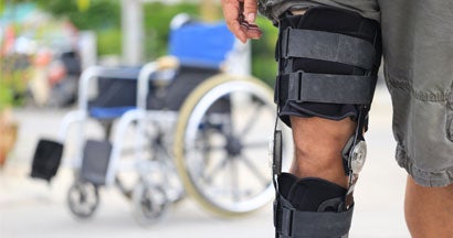 Senior man wear knee support brace on leg standing near wheelchair