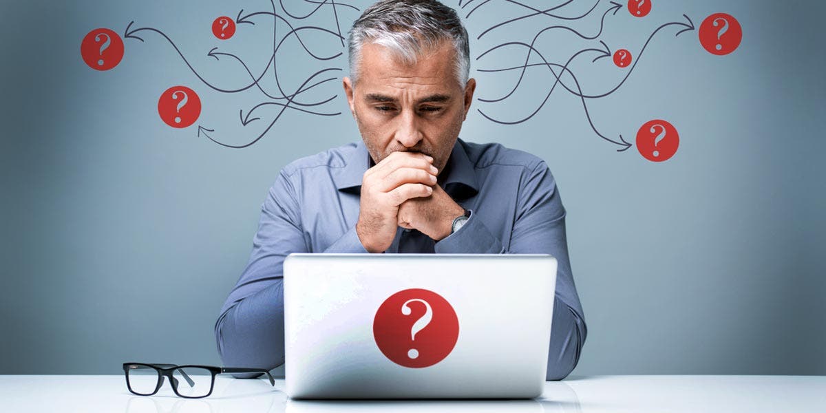 a man looking at a laptop with question marks around him