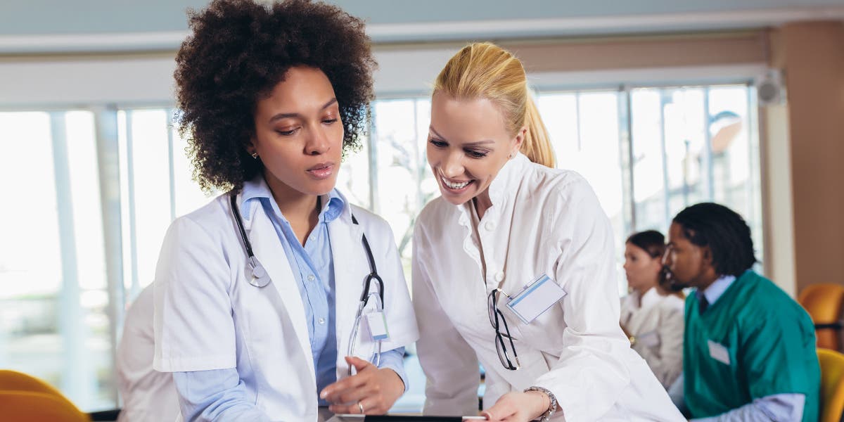 two women healthcare workers happily working together on a tablet