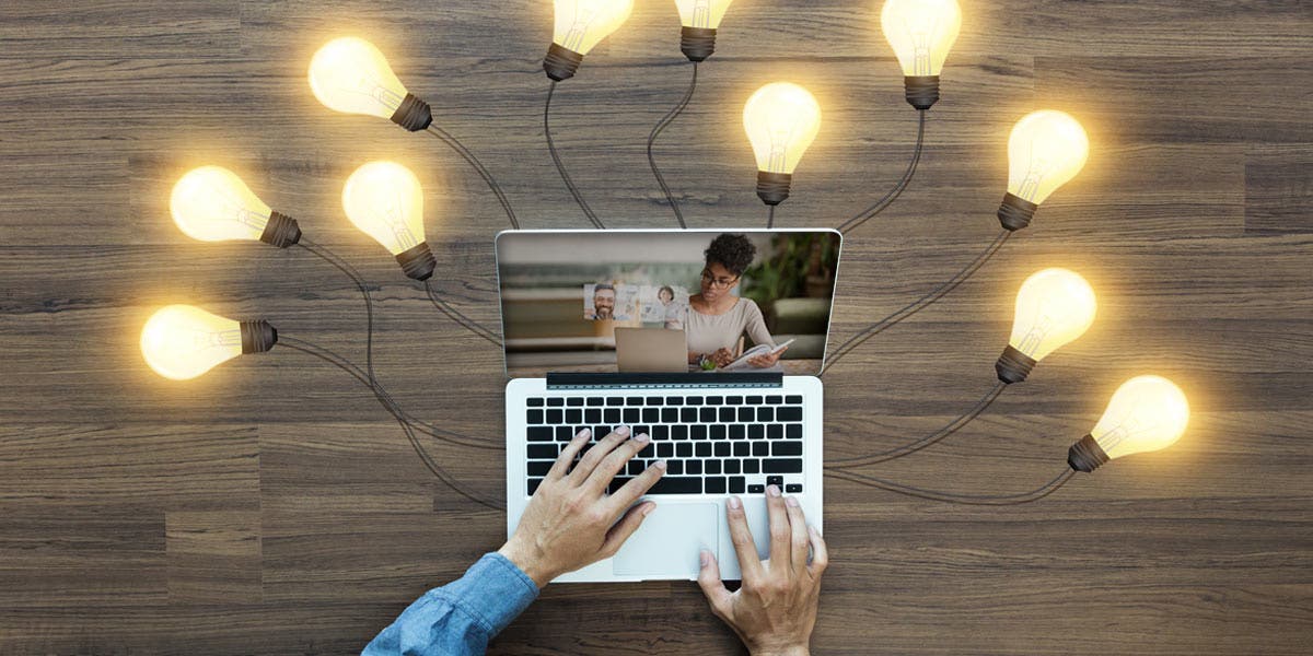 man working on a laptop with light bulbs around it 