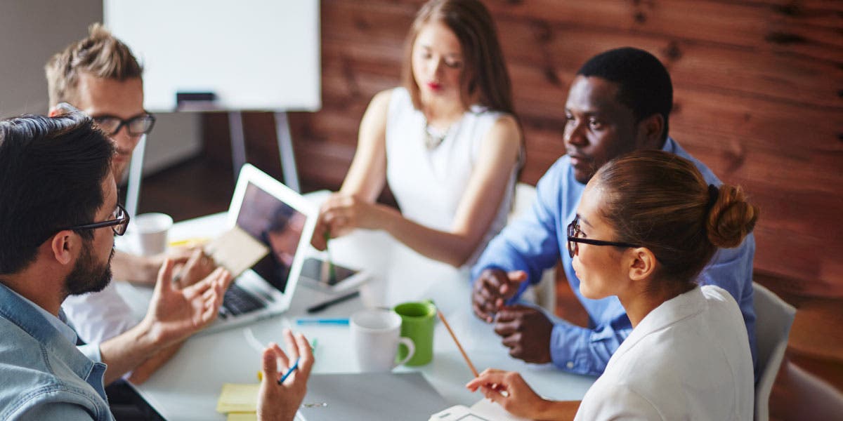 group of high potential leaders sitting at a table together, working, one leader speaking and the others looking at him?auto=format&q=75