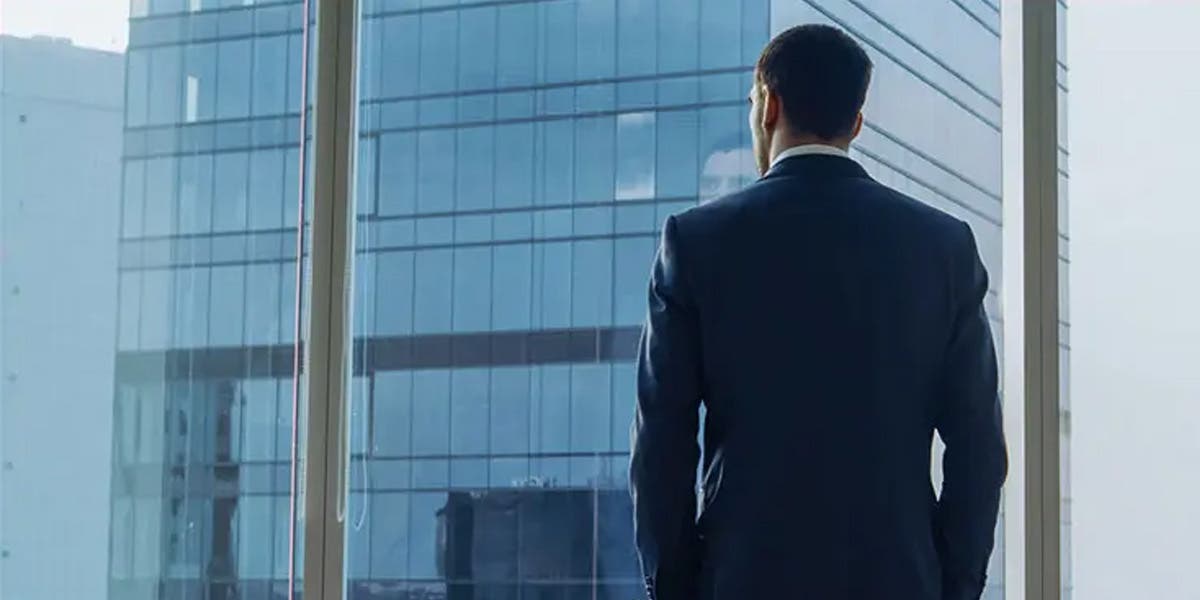 a man COO standing looking out into the distance at tall office buildings