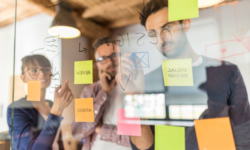 Business people meeting at office and use post it notes to share idea. Brainstorming concept. Sticky note on glass wall..jpg