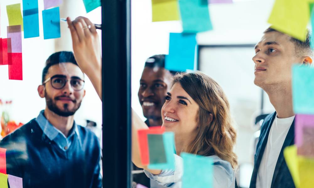 Group of colleagues share ideas by pinning sticky notes on wall.jpg