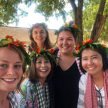image of five women smiling at the camera with a flower arrangement on their heads