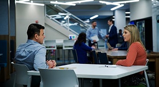 Man and a woman talking at a table in Elanco office