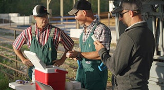 two veterinarians talking to each other with a man stood next to them