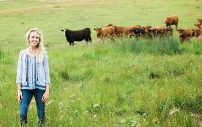 woman standing in a field of cattle