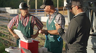 two male veterinarians stood next to a man talking